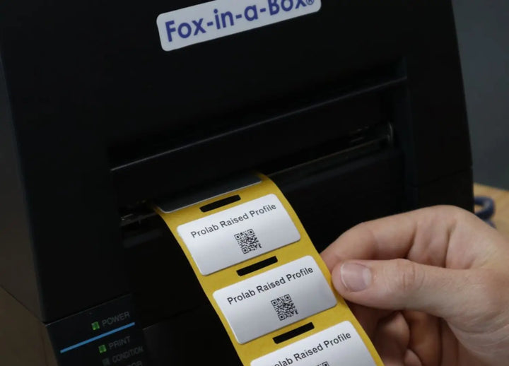 Prolab raised profile labels with QR codes feeding out of a Fox-in-a-Box printer.