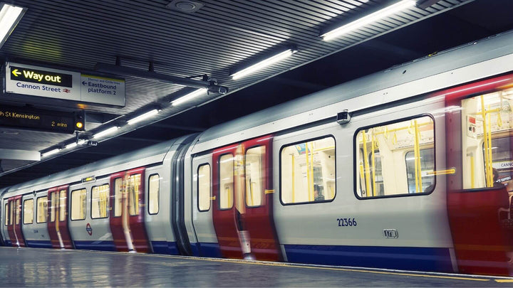 A London Underground train sits at a station platform under bright fluorescent lights, with “Way out” and Cannon Street signs overhead.
