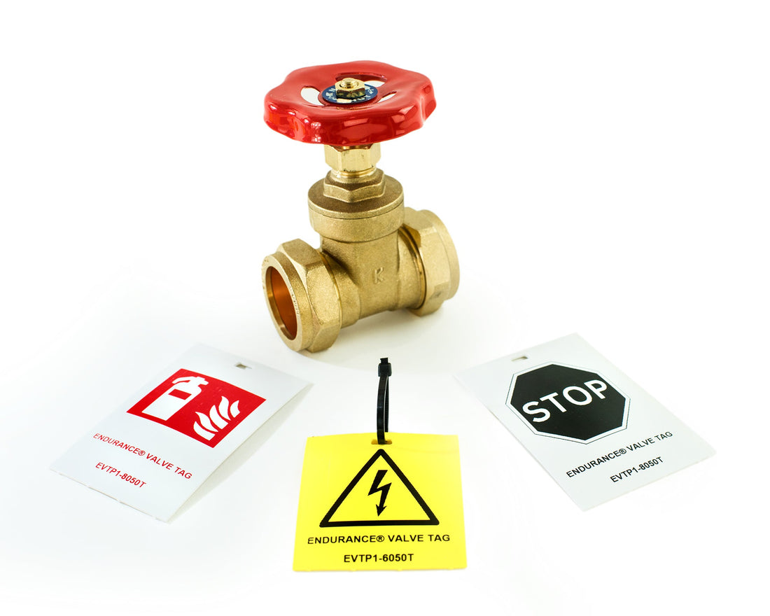 Silver Fox Endurance® Valve Tags in white and yellow displayed alongside a brass gate valve, showing printed safety symbols including fire, electrical hazard, and stop signs, with cable tie attachment, in both 60x50mm and 80x50mm sizes.