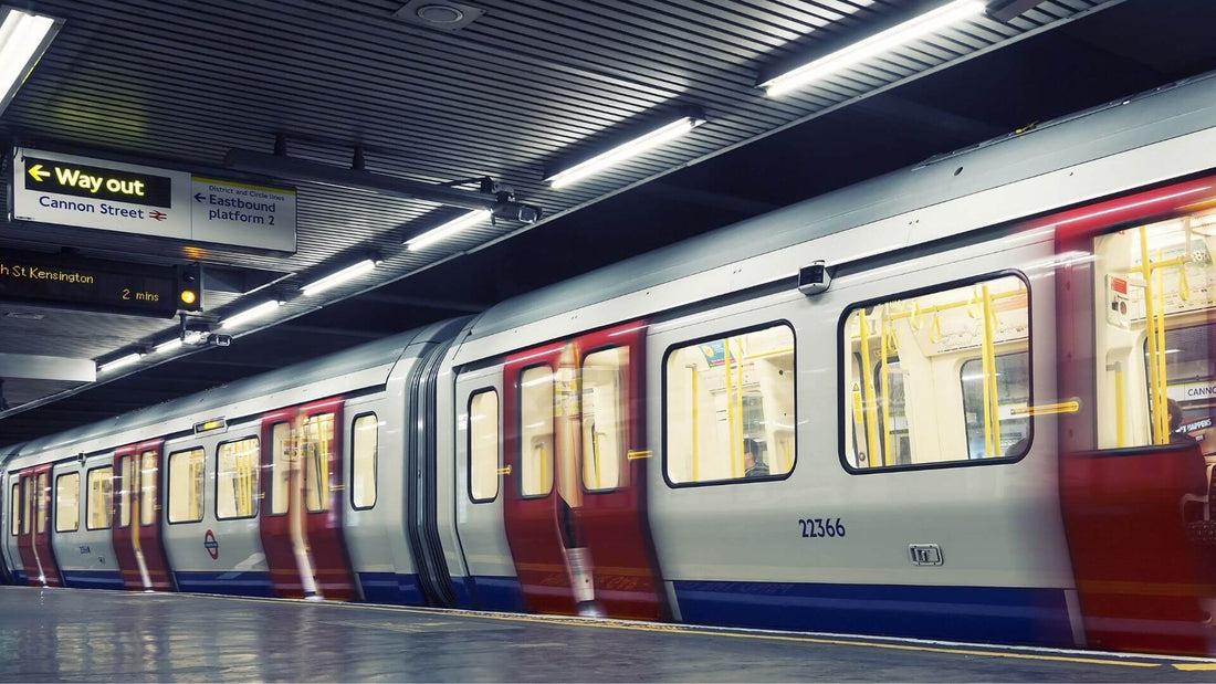 A London Underground train sits at a station platform under bright fluorescent lights, with “Way out” and Cannon Street signs overhead.